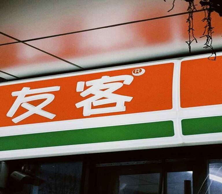 Close-up of a store sign in Chinese with orange and green colors, featuring bold white Chinese characters and an ® symbol.